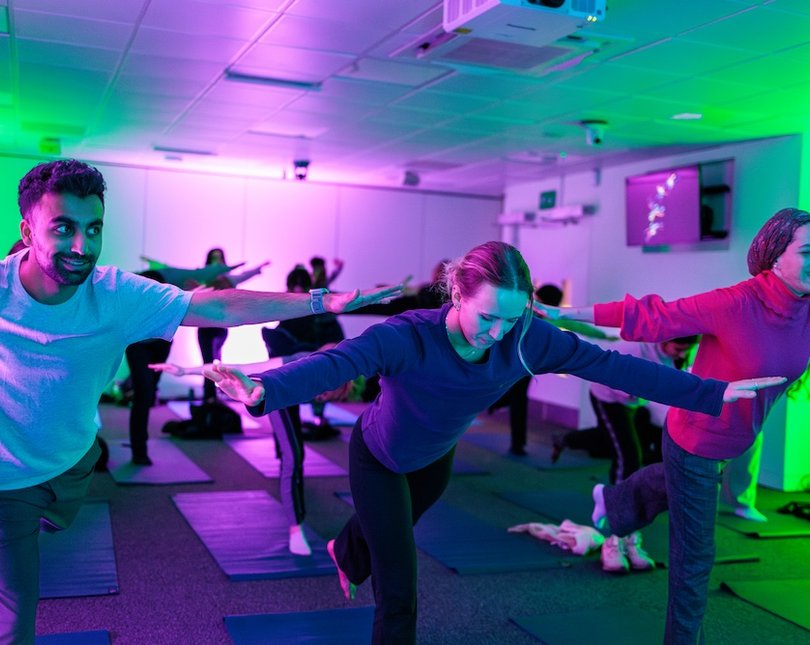 Three people leaning over in a yoga pose